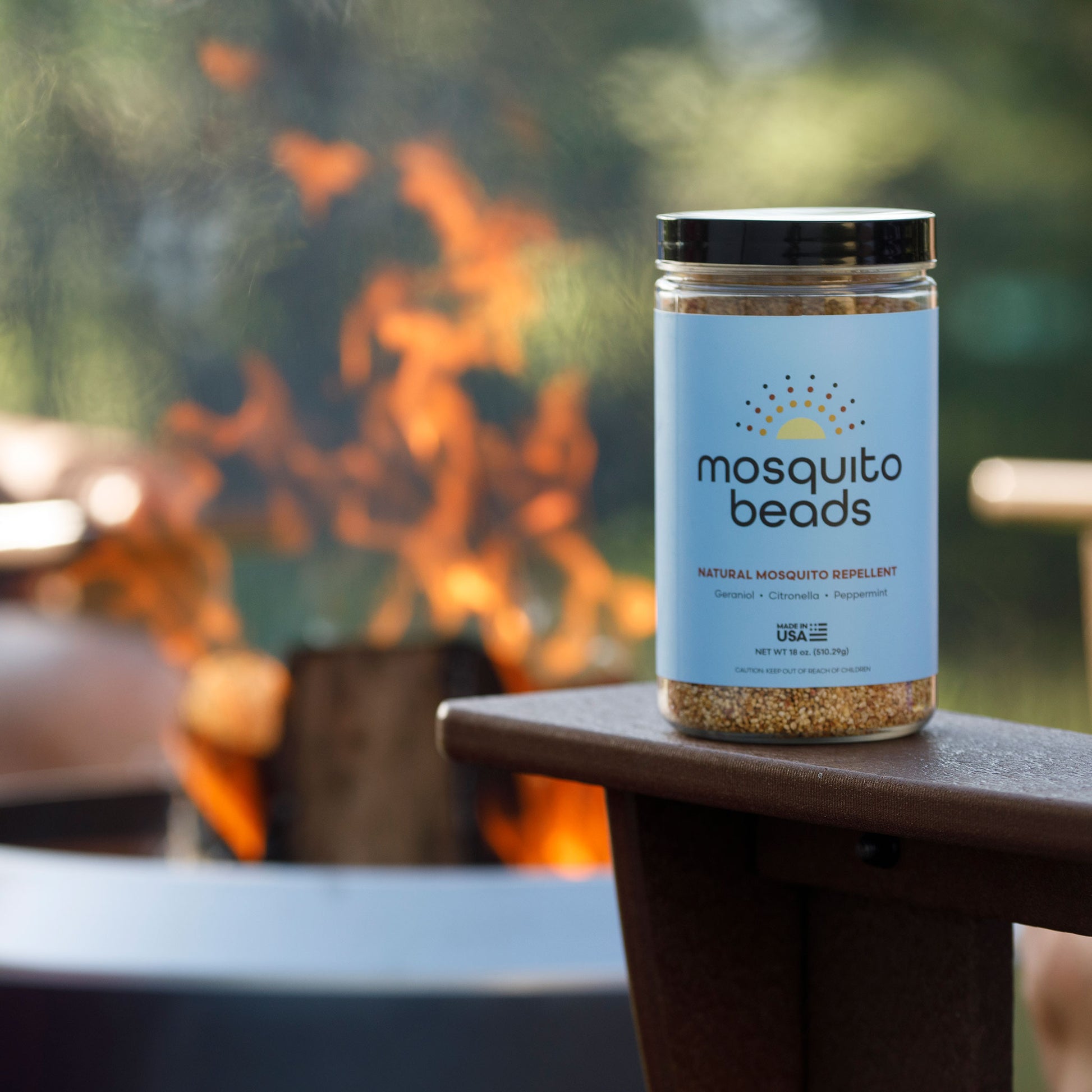 Jar of mosquito beads on a table with a fire pit in the background